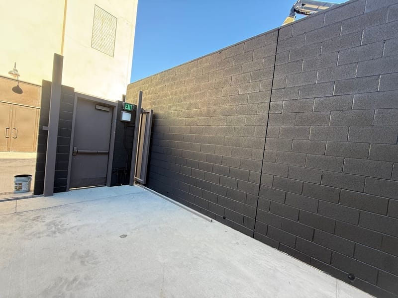 Commercial building exterior with dark painted block wall and exit door