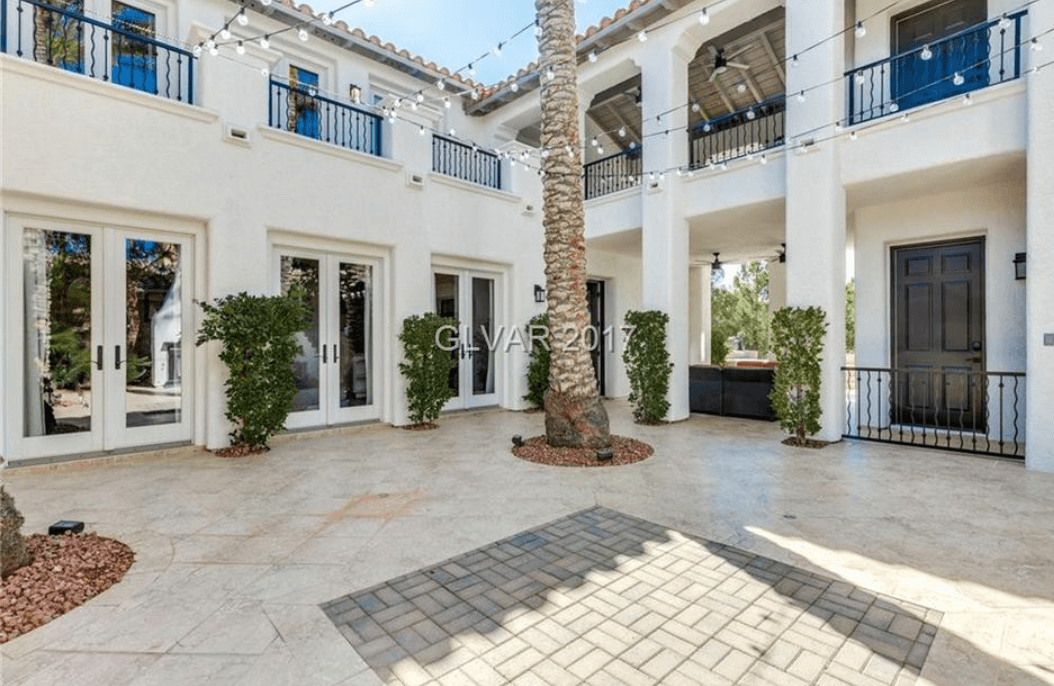 Luxury home courtyard with freshly painted white exterior and palm tree