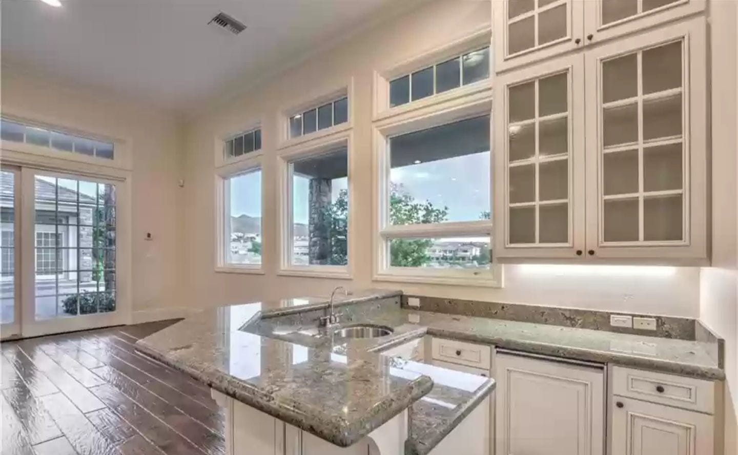 Interior kitchen with granite countertops, windows, and white cabinets.