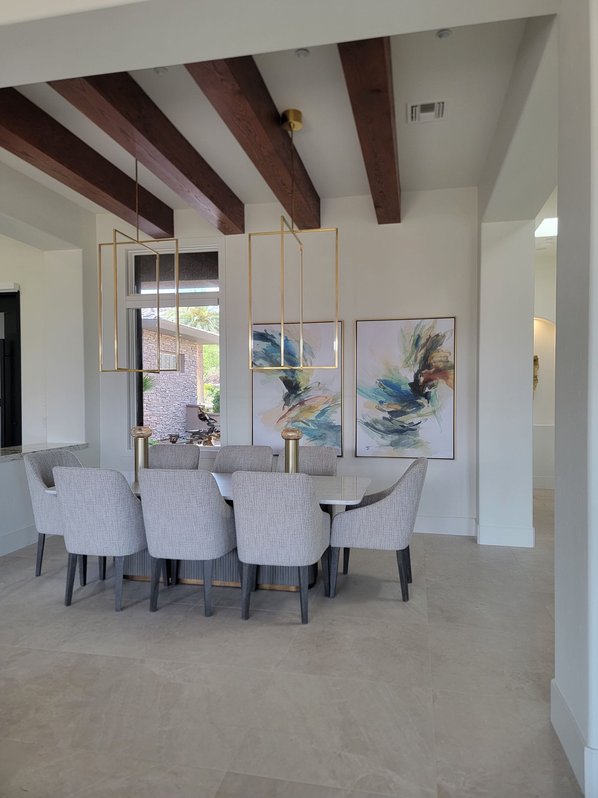Dining room with a table, chairs, artwork, and exposed wooden beams.