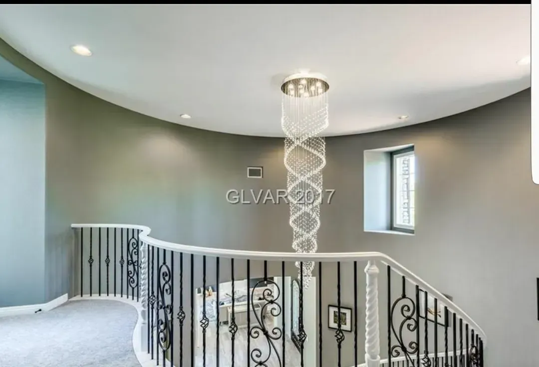 Curved staircase with a decorative railing. A crystal chandelier hangs from the ceiling.