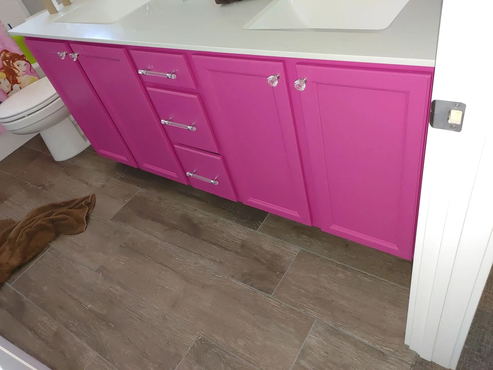 Pink bathroom vanity with white countertop and wooden floor.